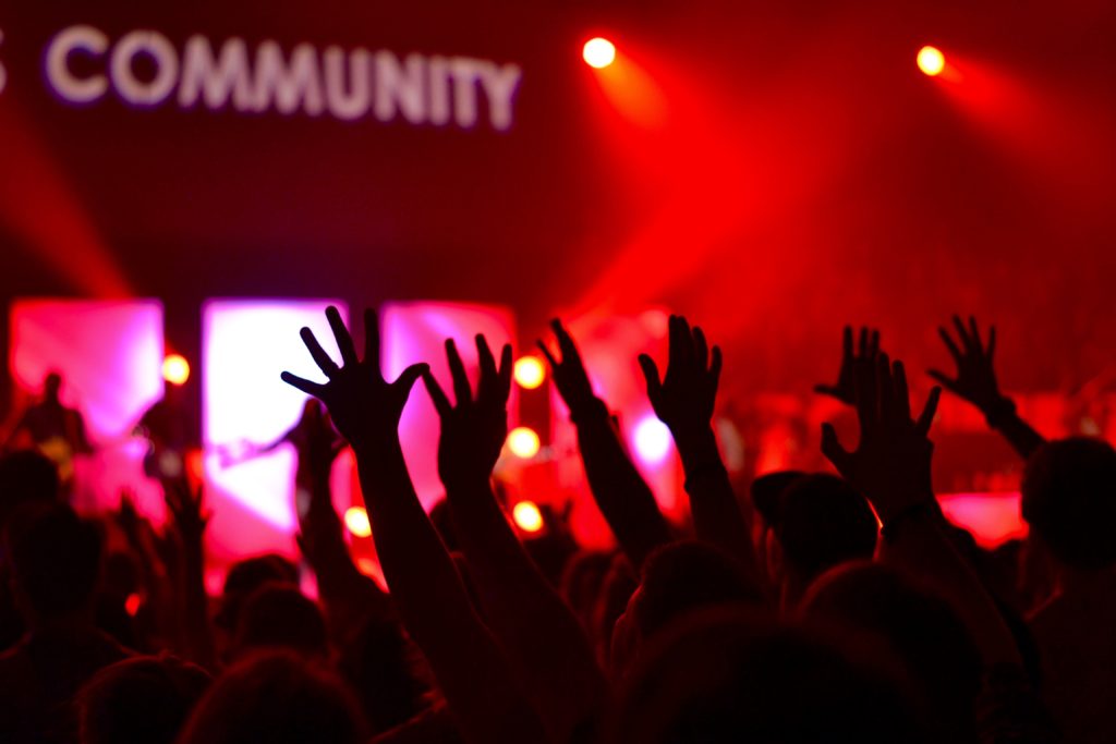 Hands raised in front of a sign proclaiming community