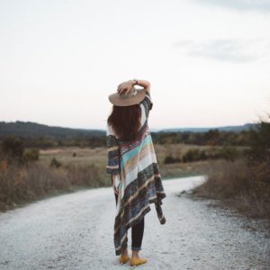 Girl in poncho and hat looking down the road